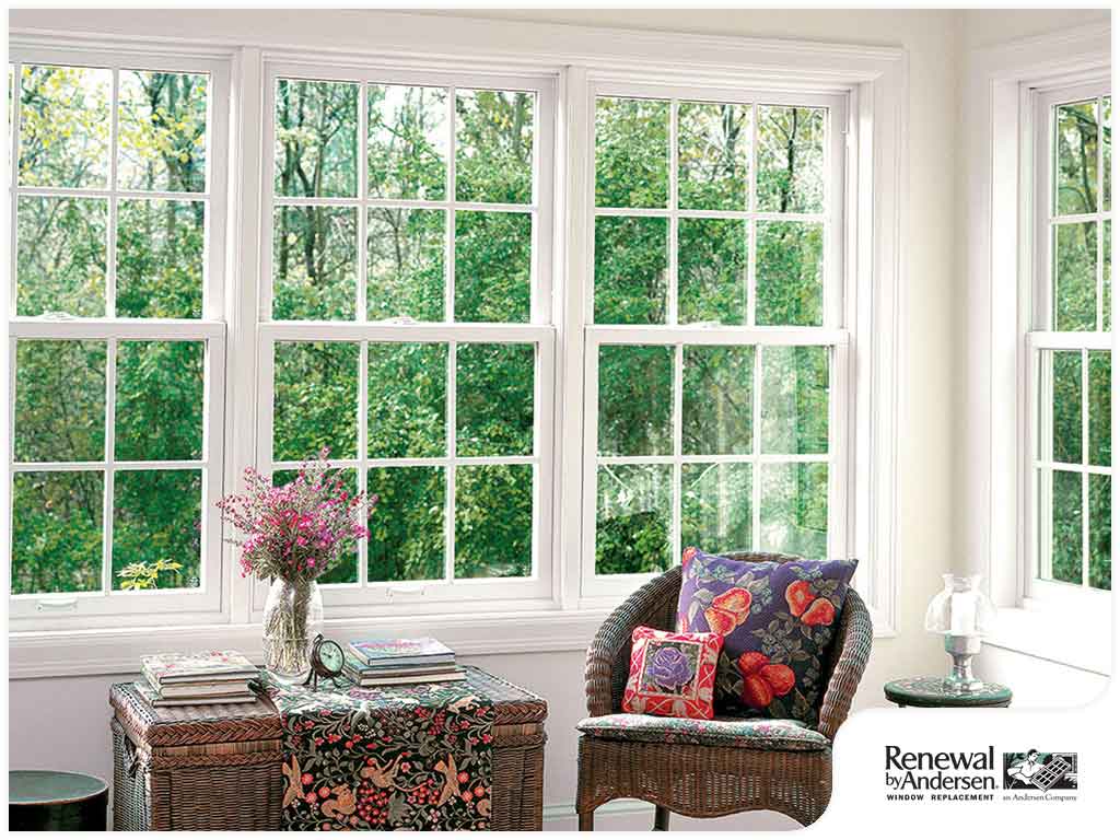 Replacement Windows Pewaukee WI Study room with woven chair, large woven chest topped with books, and four single-hung windows overlooking yard.