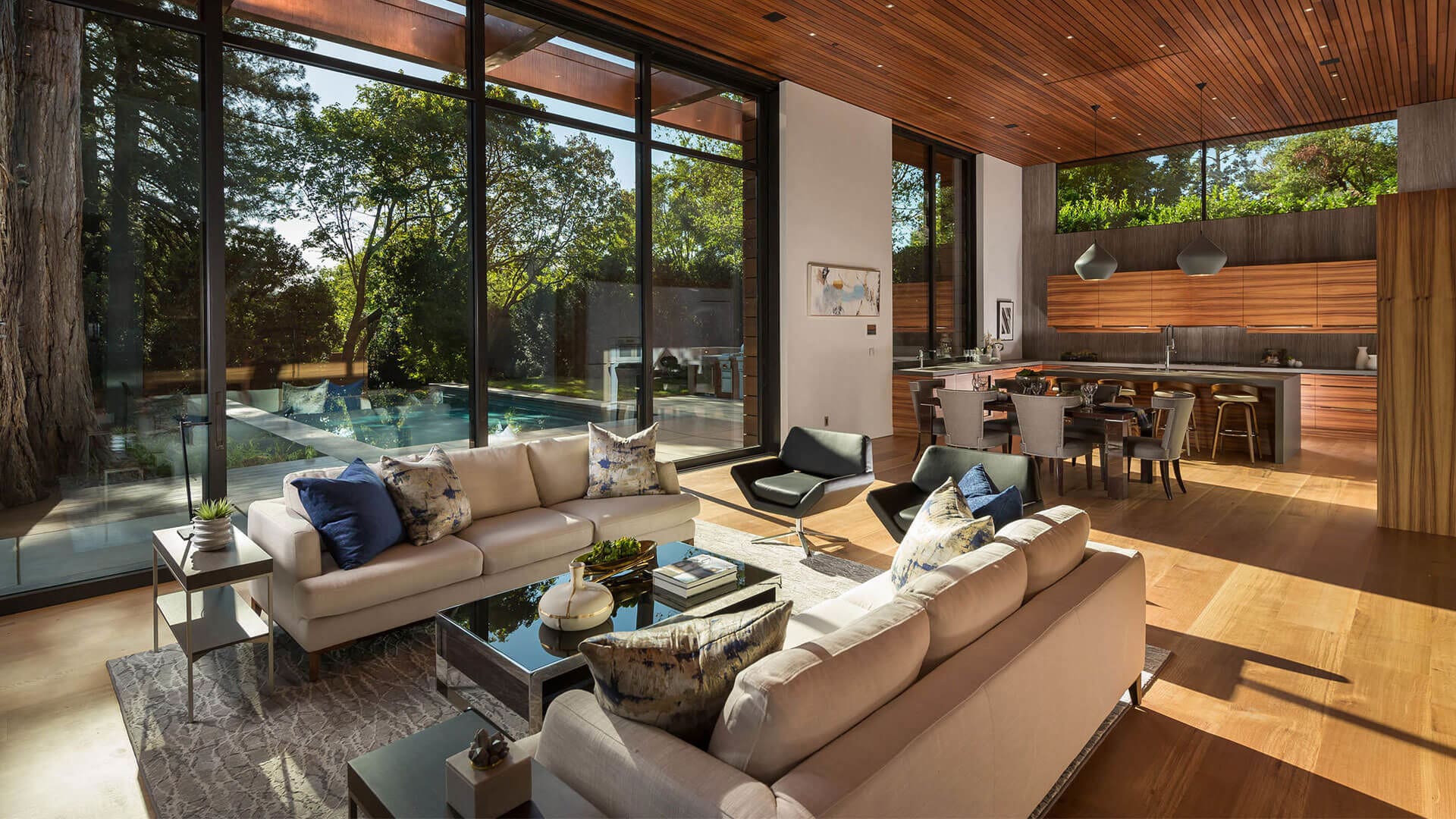 Interior view of living room with beige couches and large black frame windows.